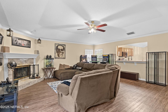 living room featuring visible vents, wood finished floors, a premium fireplace, and crown molding