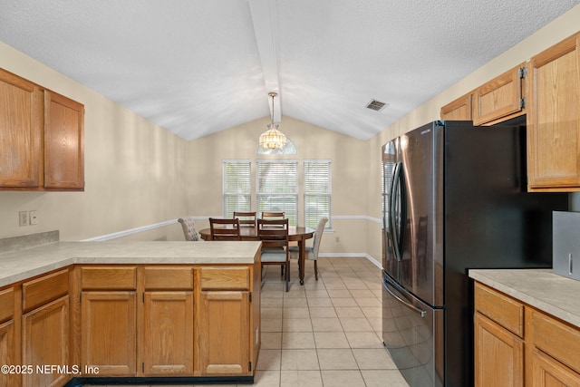 kitchen with visible vents, light countertops, a peninsula, freestanding refrigerator, and light tile patterned flooring