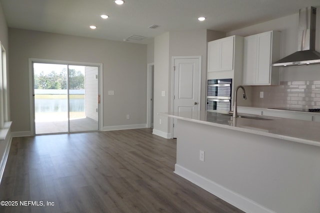 kitchen with a sink, backsplash, dark wood finished floors, wall chimney exhaust hood, and black electric cooktop