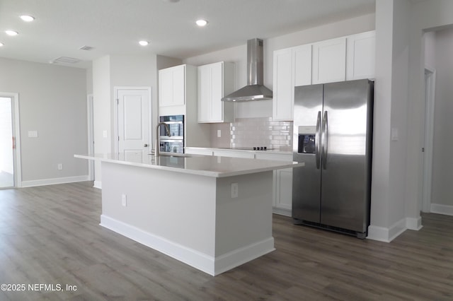 kitchen with a center island with sink, white cabinets, stainless steel appliances, and wall chimney exhaust hood