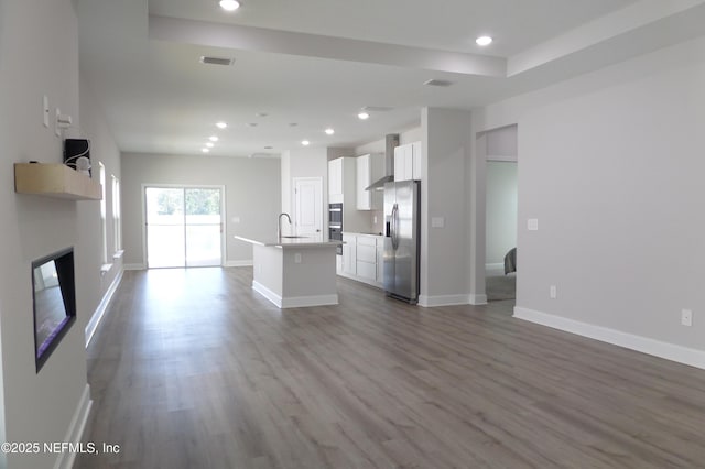 unfurnished living room with a sink, recessed lighting, a fireplace, baseboards, and dark wood-style flooring