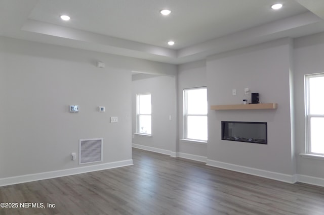 unfurnished living room featuring a glass covered fireplace, a healthy amount of sunlight, visible vents, and baseboards