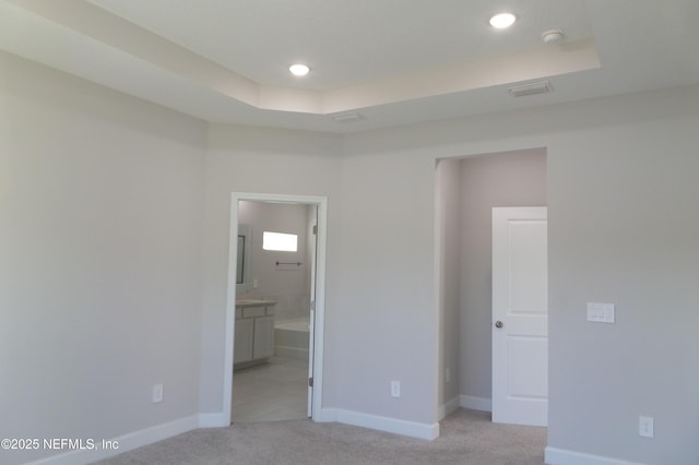 unfurnished room with visible vents, baseboards, light carpet, recessed lighting, and a raised ceiling