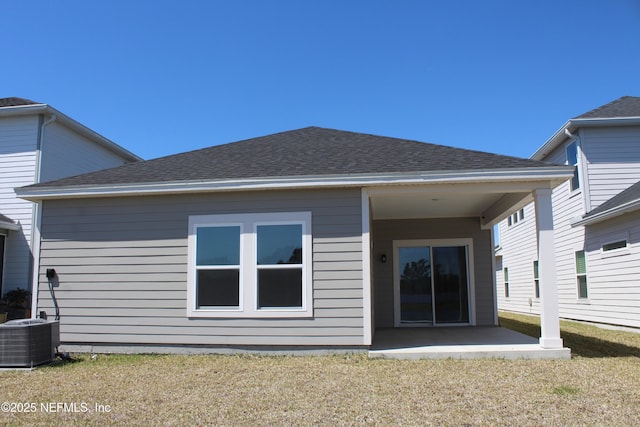 back of house featuring cooling unit, a yard, roof with shingles, and a patio area