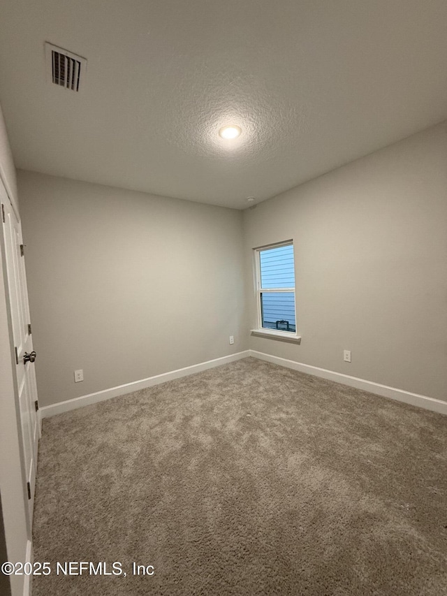 unfurnished room featuring baseboards, carpet, visible vents, and a textured ceiling