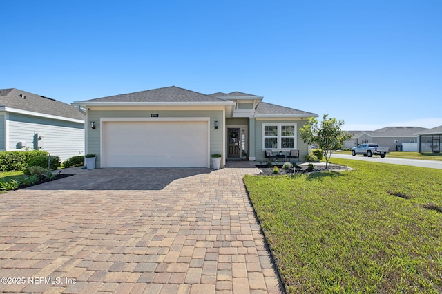 view of front of property featuring decorative driveway, a front yard, and an attached garage