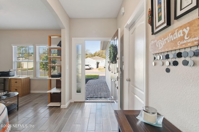 entrance foyer with baseboards, arched walkways, and wood tiled floor