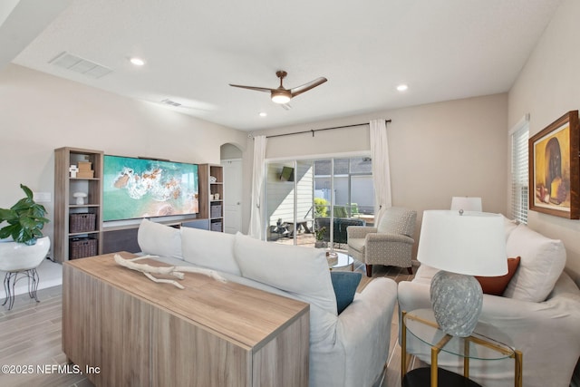 living area with a ceiling fan, visible vents, light wood finished floors, recessed lighting, and arched walkways