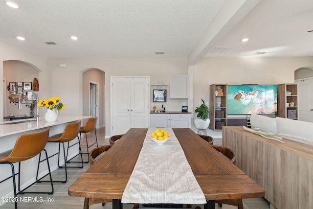 dining space with arched walkways, visible vents, and recessed lighting