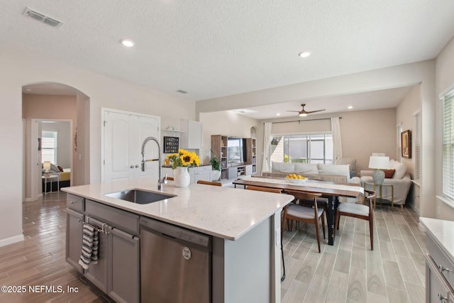 kitchen with visible vents, gray cabinets, arched walkways, a sink, and dishwasher