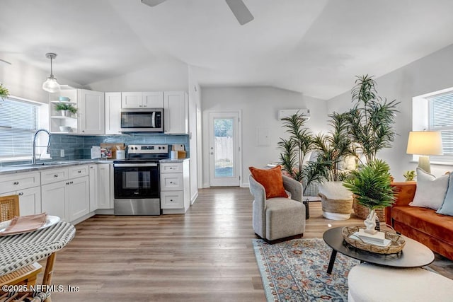 kitchen featuring a sink, vaulted ceiling, white cabinets, and stainless steel appliances