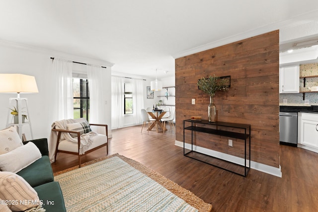 living room with dark wood finished floors, crown molding, bar, and baseboards