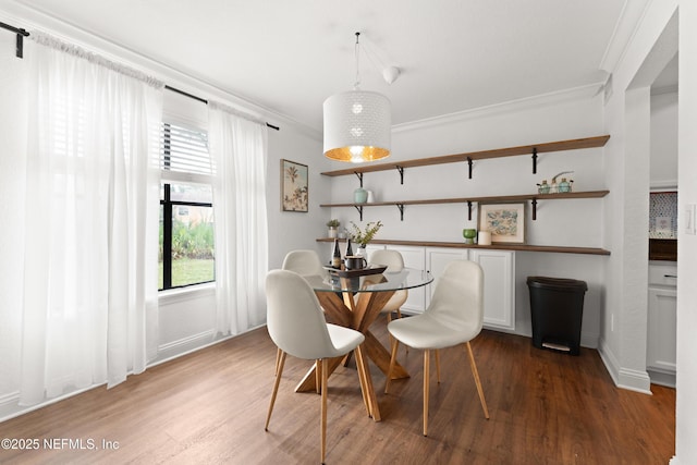 dining space featuring wood finished floors, baseboards, and ornamental molding