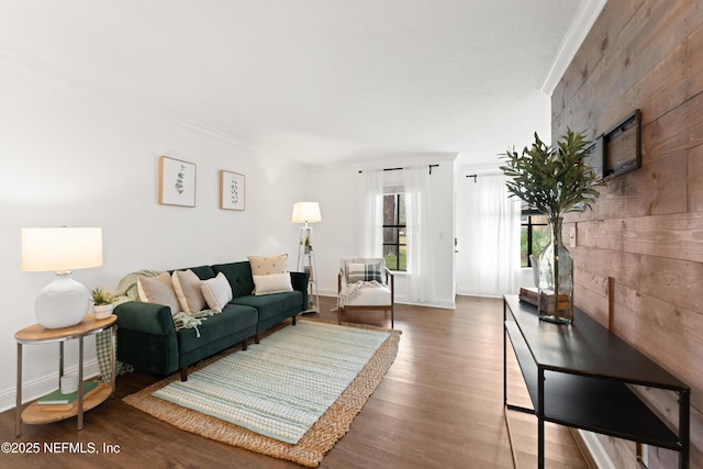 living area with wood finished floors, baseboards, and ornamental molding