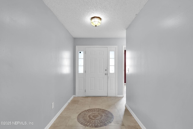 entryway featuring light tile patterned floors, baseboards, and a textured ceiling