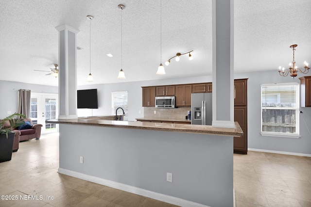 kitchen with tasteful backsplash, plenty of natural light, ceiling fan with notable chandelier, and stainless steel appliances