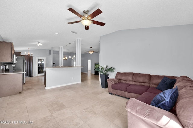 living room featuring visible vents, ceiling fan with notable chandelier, a textured ceiling, baseboards, and vaulted ceiling