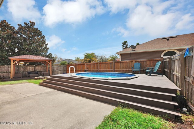 view of pool with a fenced in pool, a wooden deck, a fenced backyard, a gazebo, and a patio area