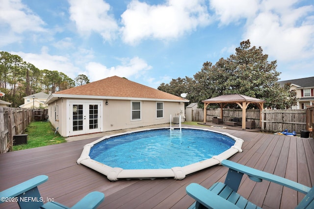 view of pool featuring a fenced in pool, a fenced backyard, a gazebo, french doors, and a deck