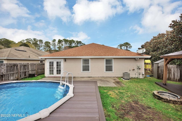 view of swimming pool featuring a fenced in pool, central air condition unit, a lawn, french doors, and a fenced backyard