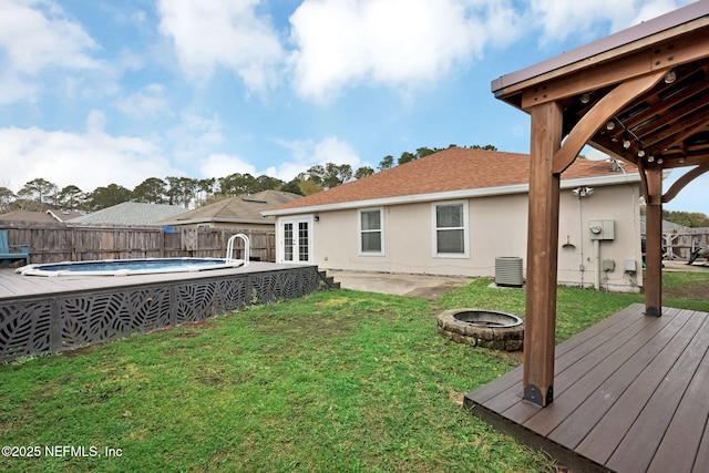 view of yard featuring a fenced in pool, a fire pit, fence, central air condition unit, and a deck