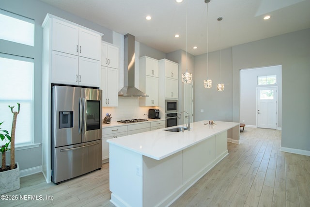 kitchen featuring a sink, tasteful backsplash, a spacious island, stainless steel appliances, and wall chimney range hood