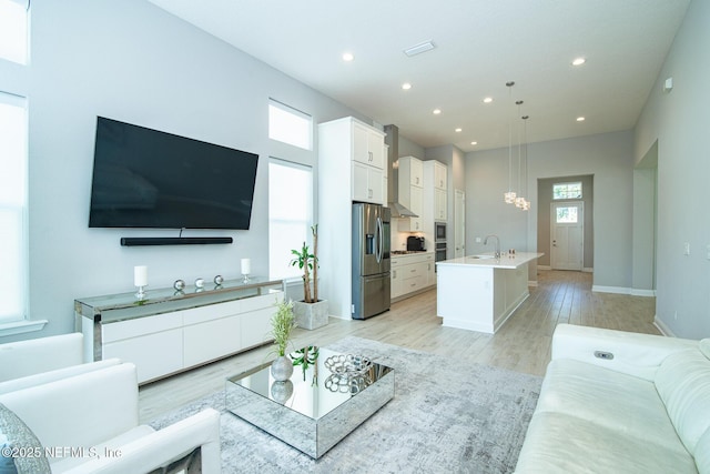 living area featuring recessed lighting, baseboards, plenty of natural light, and light wood-style floors