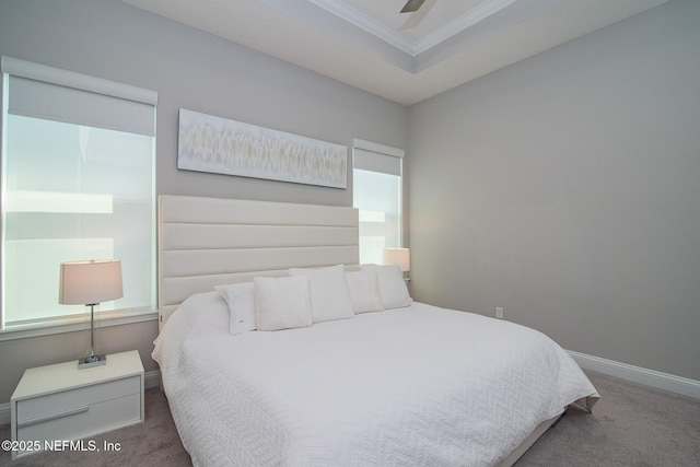 carpeted bedroom with ceiling fan, a tray ceiling, baseboards, and ornamental molding