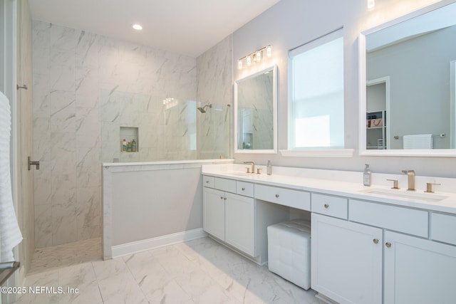 bathroom with double vanity, marble finish floor, a marble finish shower, and a sink