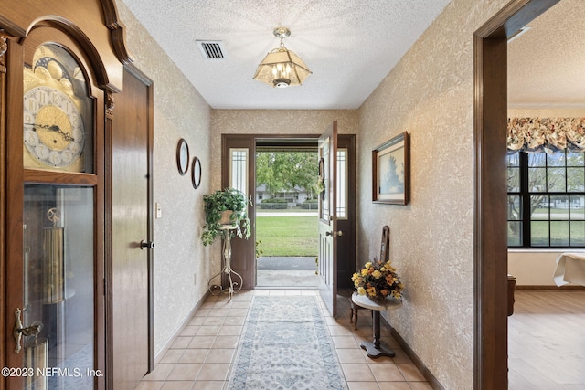 entrance foyer featuring visible vents, a textured ceiling, and a textured wall