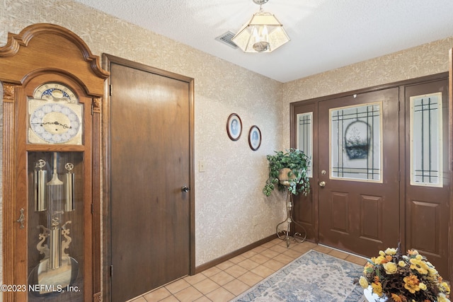 entrance foyer featuring wallpapered walls, light tile patterned floors, and baseboards