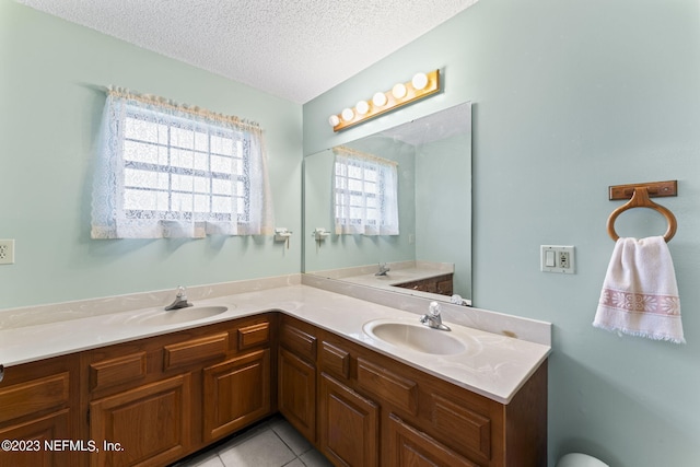 full bathroom with tile patterned floors, double vanity, a textured ceiling, and a sink