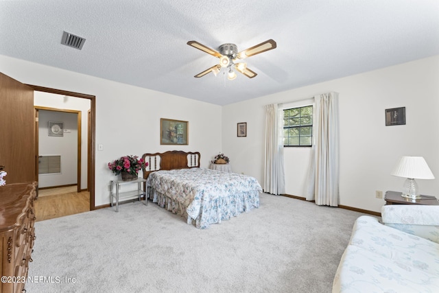 bedroom with visible vents, light carpet, a ceiling fan, a textured ceiling, and baseboards