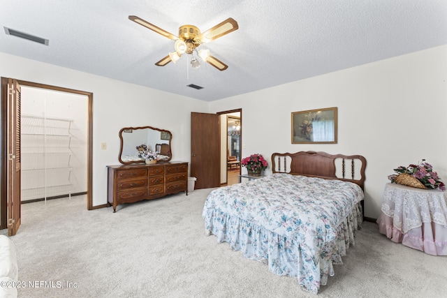 bedroom with a ceiling fan, carpet, visible vents, and a textured ceiling