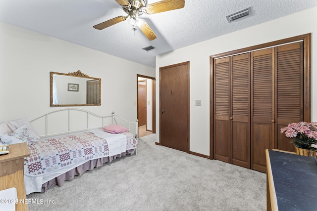 bedroom with visible vents, carpet floors, two closets, and a textured ceiling