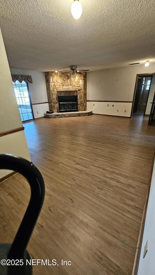 unfurnished living room featuring wood finished floors, a fireplace, and a textured ceiling