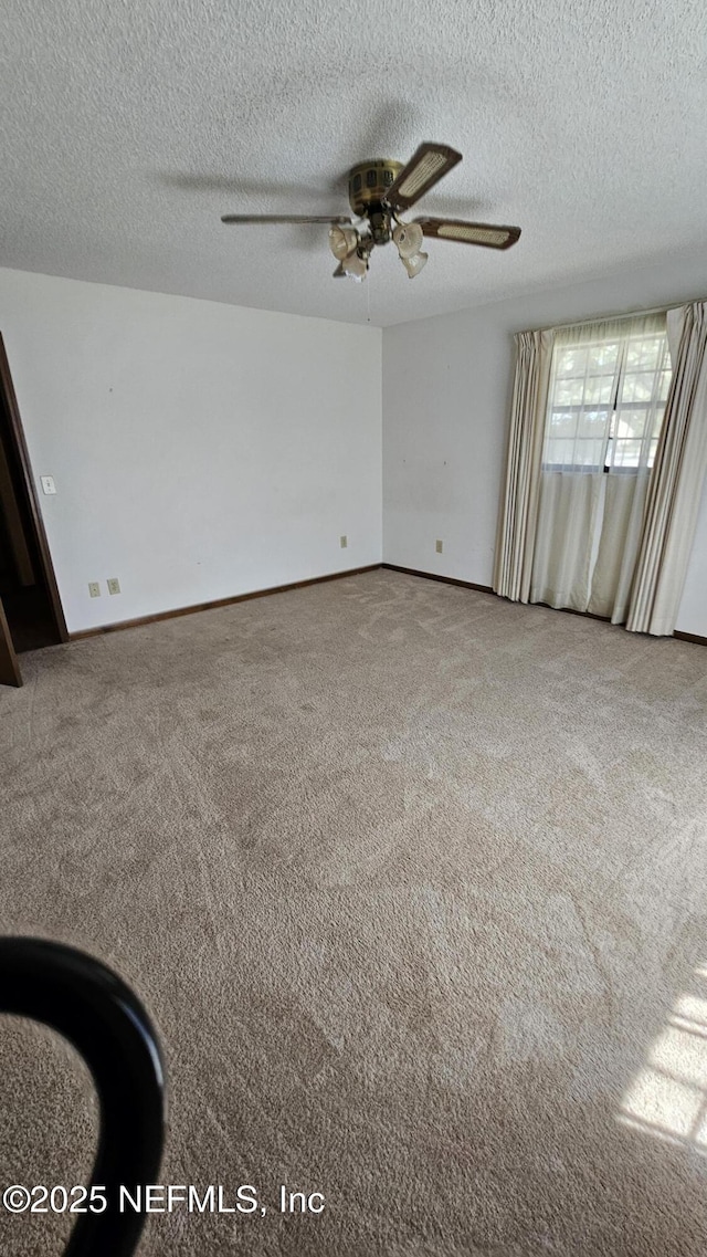 empty room featuring baseboards, carpet, a ceiling fan, and a textured ceiling