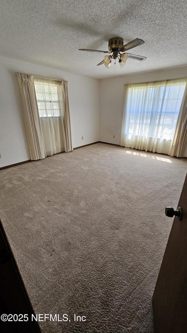 carpeted empty room with baseboards, a textured ceiling, and a ceiling fan