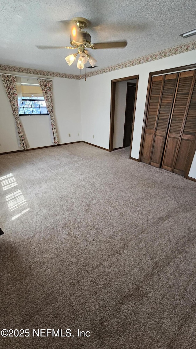 unfurnished bedroom with baseboards, multiple closets, a textured ceiling, and carpet floors