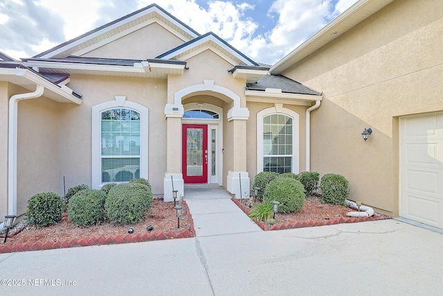 view of exterior entry with stucco siding and a garage