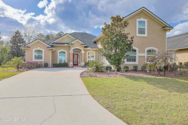 traditional home with stucco siding, concrete driveway, and a front yard