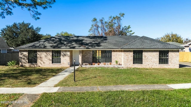 ranch-style home featuring brick siding, a front lawn, and fence