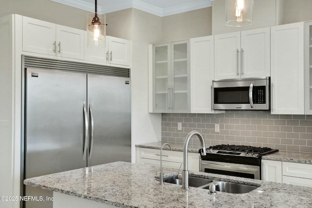 kitchen with tasteful backsplash, crown molding, appliances with stainless steel finishes, white cabinets, and a sink