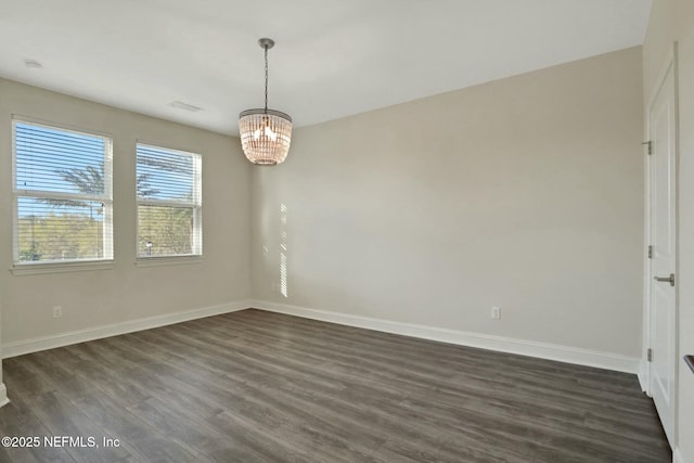 spare room featuring dark wood-style floors, baseboards, visible vents, and a chandelier