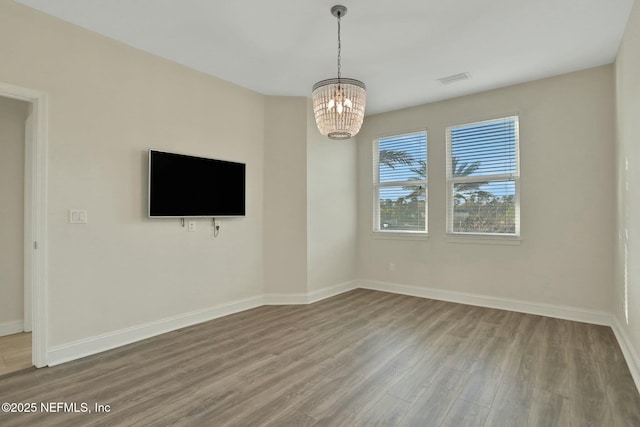 interior space with baseboards, an inviting chandelier, and wood finished floors