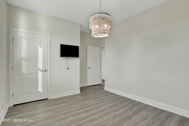 interior space featuring baseboards, wood finished floors, and a chandelier