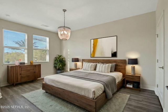 bedroom featuring visible vents, baseboards, an inviting chandelier, and wood finished floors