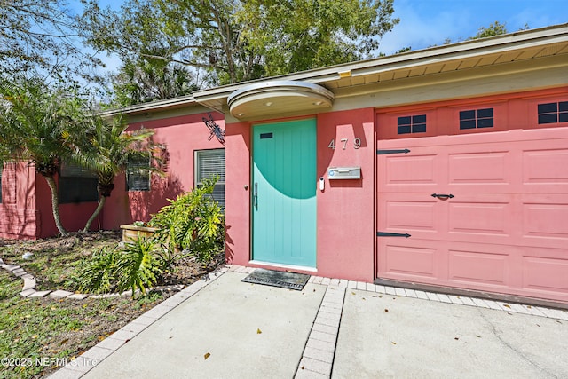 entrance to property featuring a garage and stucco siding