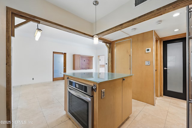 kitchen featuring stainless steel oven, pendant lighting, light tile patterned floors, and a center island