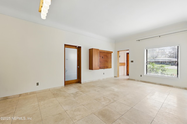 spare room with light tile patterned floors and baseboards